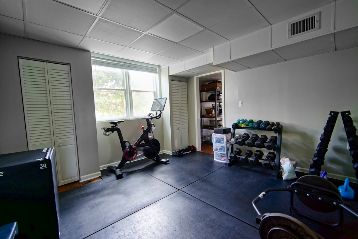 Basement home gym with Peloton bike, dumbbell rack, and rubber flooring