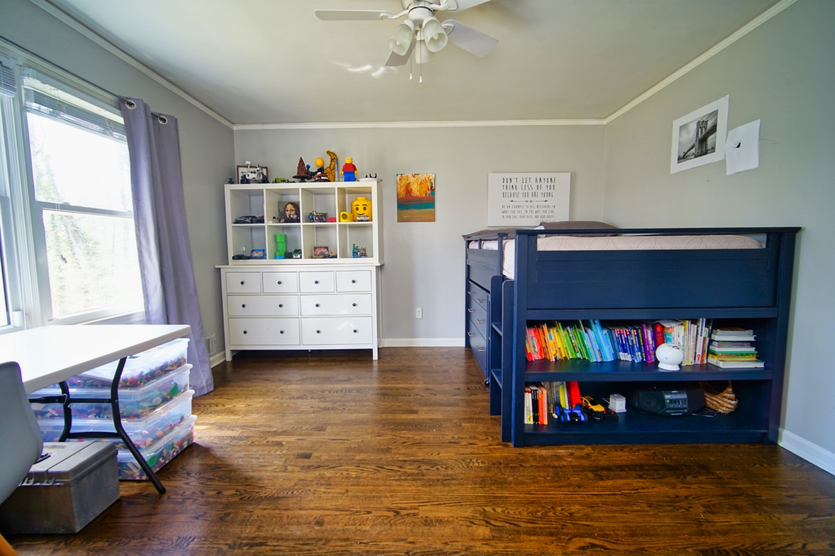 Bedroom with loft bed, bookshelf, and hardwood floors