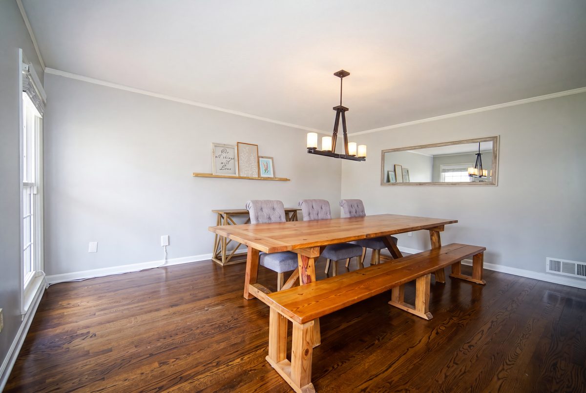 Dining room with farmhouse table, bench seating, chandelier, and hardwood floors