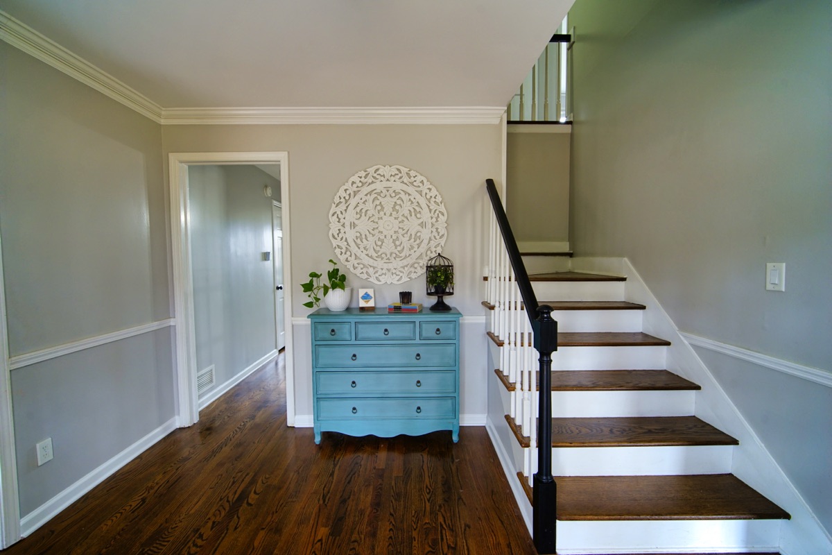Welcoming foyer with hardwood floors, staircase, and decorative accents