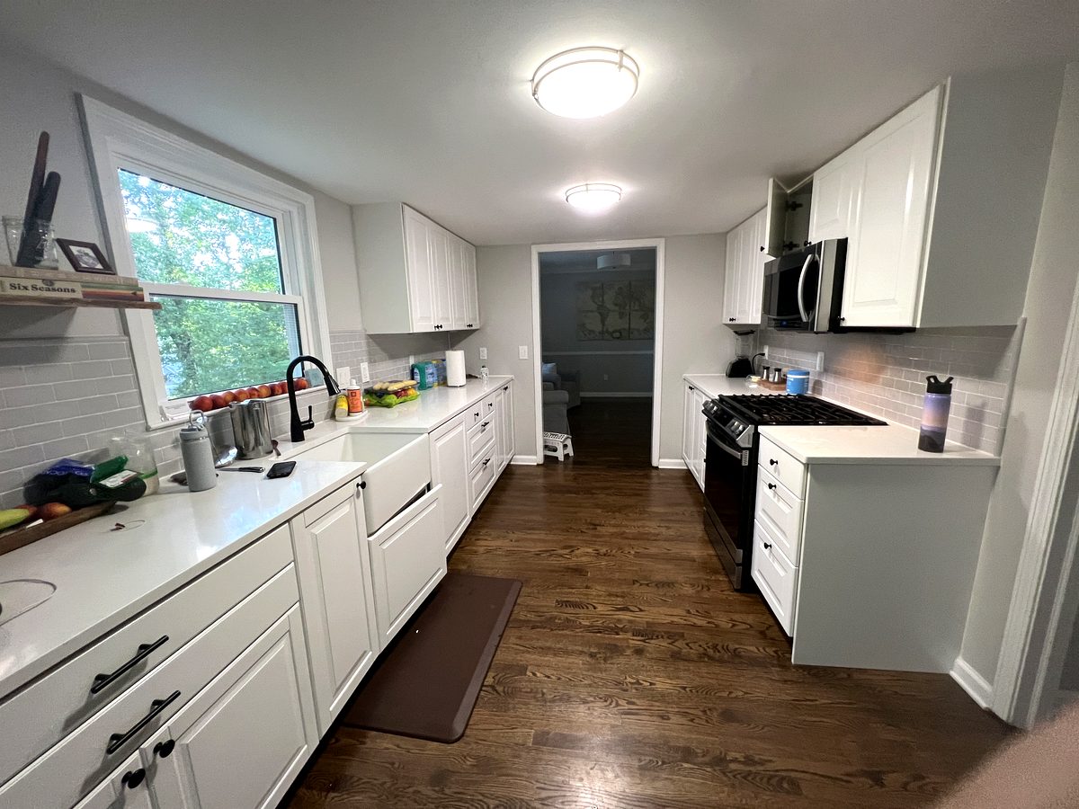 Galley kitchen with farmhouse sink, subway tile backsplash, and natural light