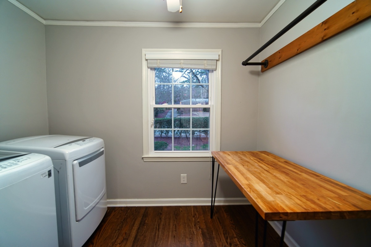 Laundry room with washer, dryer, butcher block folding counter, and hanging rack