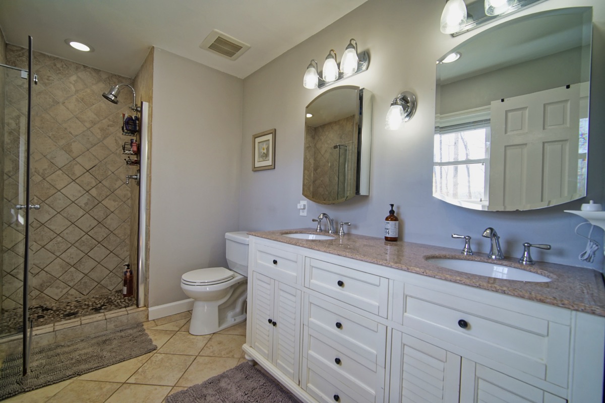 Master bathroom with double vanity, walk-in tile shower, and granite countertops
