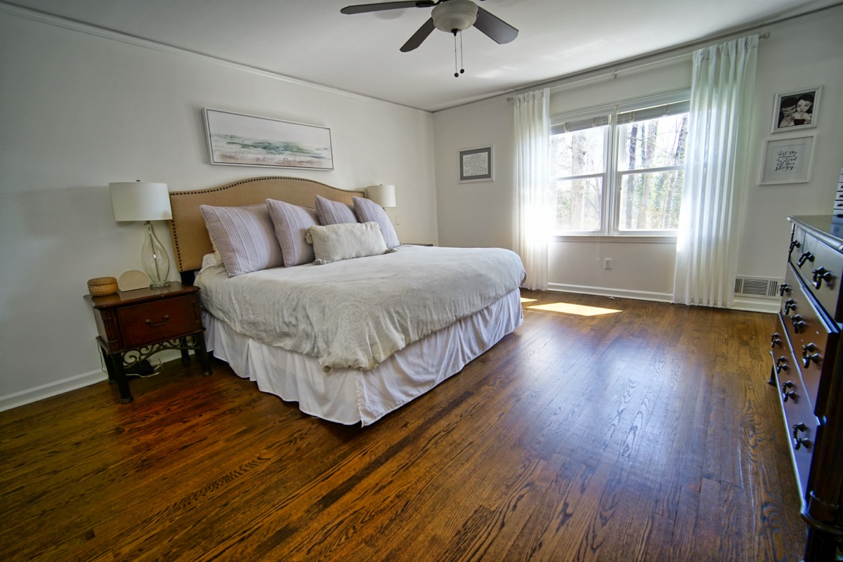 Spacious master bedroom with king bed, ceiling fan, and hardwood floors